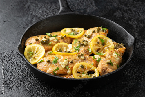 Chicken Piccata with capers, white wine sauce in iron cast pan. Italian food photo