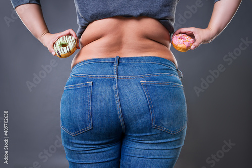 Obraz na plátně Fat woman posing with donuts on a gray background