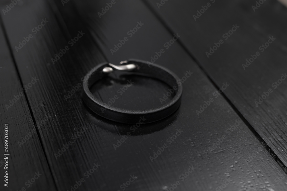 Black leather male bracelet on the dark wooden desk Black leather male bracelet on the dark wooden desk