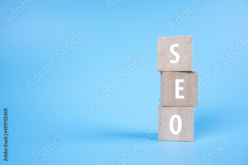 SEO or search engine optimization on a wooden block over blue background