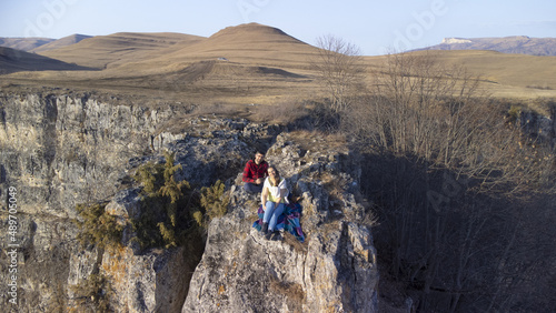 Couple in love sits on a cliff in the mountains winter landscape