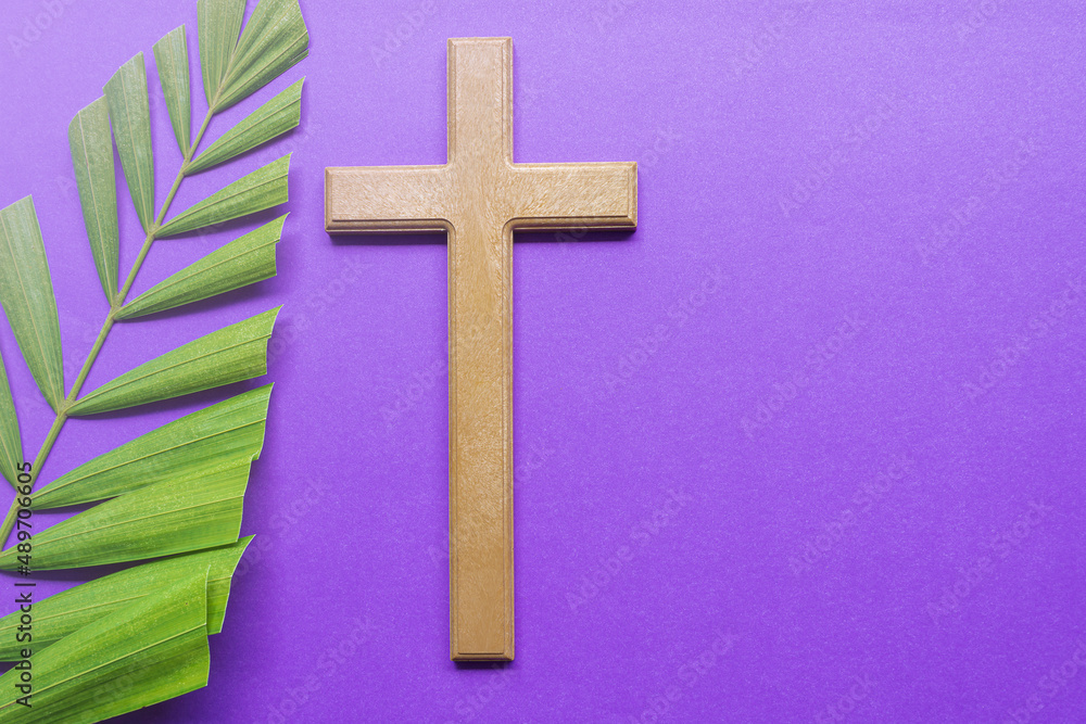 Cross and palm leaves on purple background. Lent season concept.
