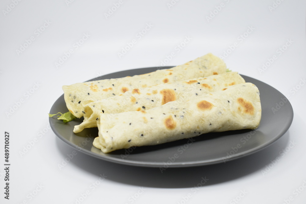 Arabic pita with cheese and greens on a gray plate. Light gray background.