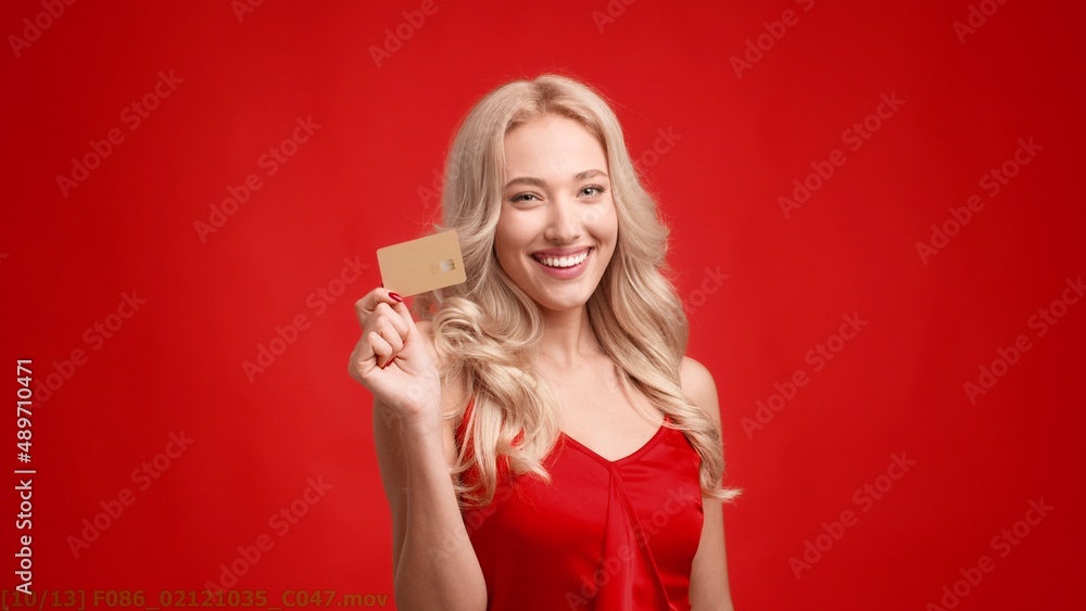 Happy Blonde Lady Holding Credit Card Winking Eye, Red Background Happy Blonde Lady Holding Credit Card Winking Eye, Red Background