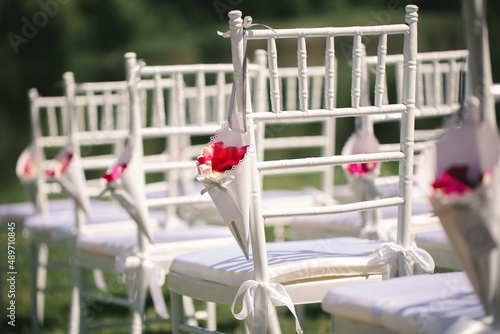 White chairs at the wedding ceremony with rose petals.