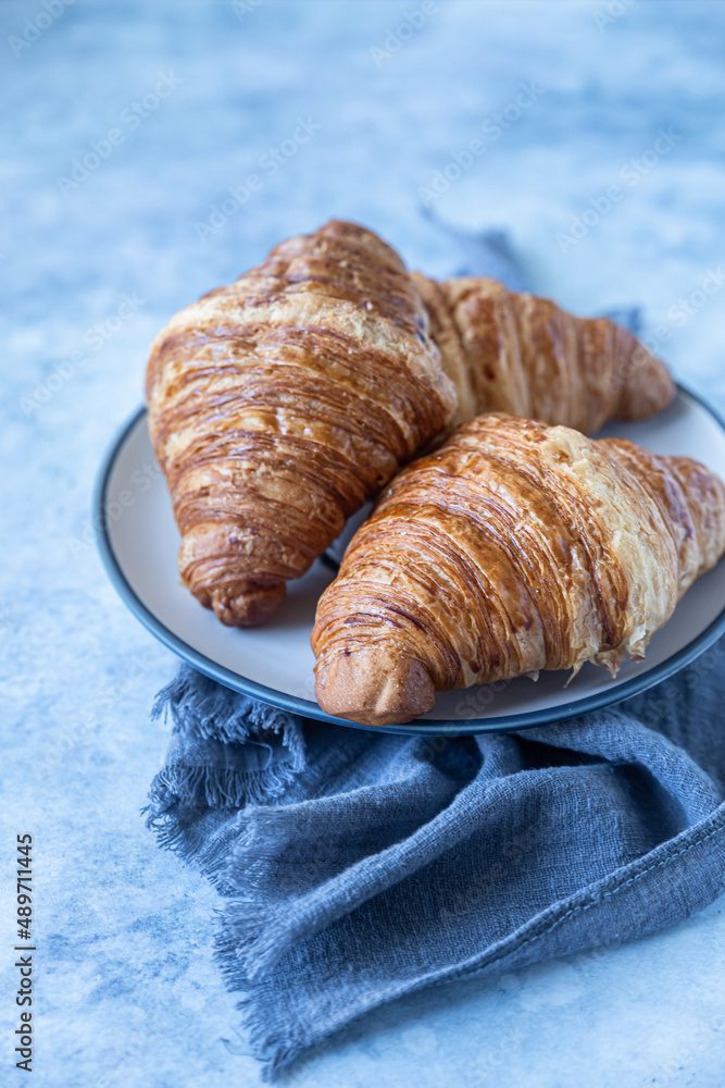 Tasty crispy croissants, blue background. Bakery for breakfast.