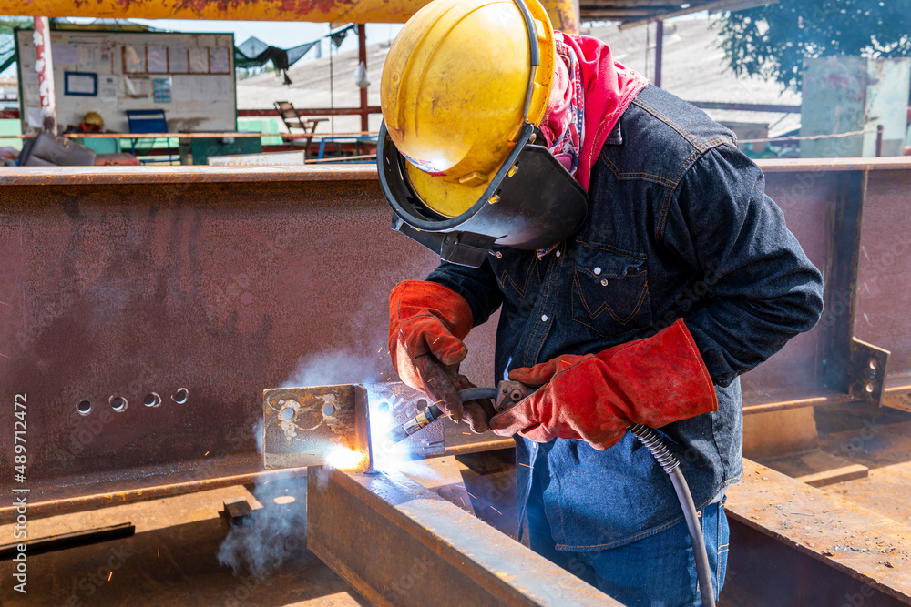 Welder is welding a steel plate for steel structure work with process