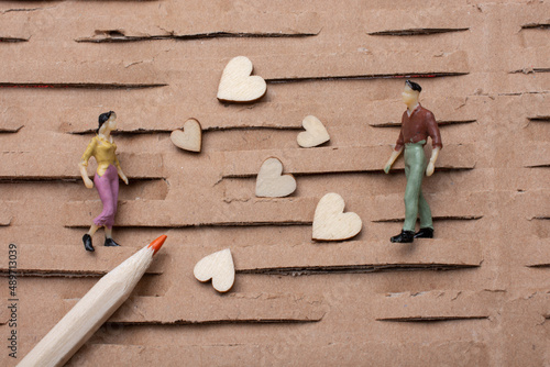 Tiny figurine of man and woman models  and heart icons  and color pencil photo