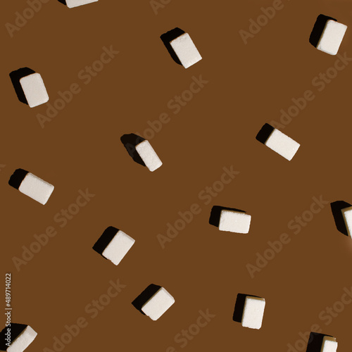 Attractive and modern pattern of sugar cubes with a sharp shadow on a coffee-brown background photo