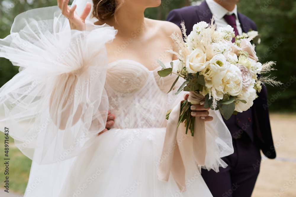 Naklejka premium The bride in an elegant dress holds a wedding bouquet