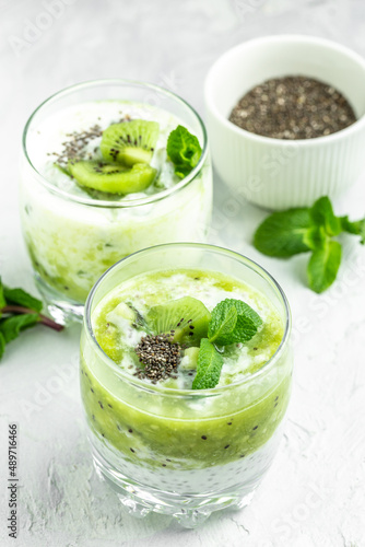 Healthy breakfast chia pudding with kiwi in glass jars on a white table. Clean eating, dieting, vegan food concept. vertical image