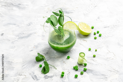 Refreshing kale cucumber green smoothie in a glass on concrete background. Detox smoothie, green fresh peas, cucumber, radish, spinach and lime. top view