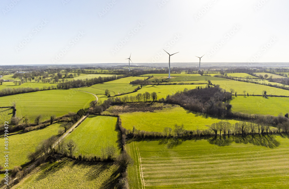 Many wind turbine in the middle of the fields in the French countryside - renewable energy source, green energy against global warming - drone view