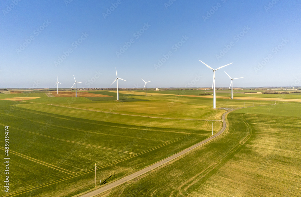 Many wind turbine in the middle of the fields in the French countryside - renewable energy source, green energy against global warming - drone view Many wind turbine in the middle of the fields in the French countryside - renewable energy source, green energy against global warming - drone view
