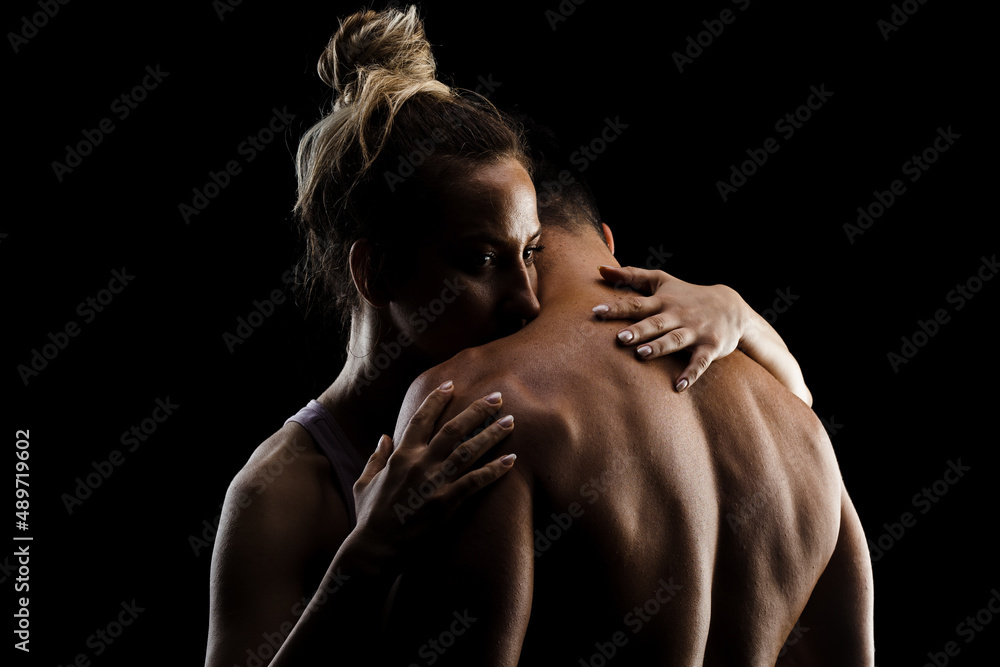 Fit couple posing together. Boy and girl side lit silhouettes on black background. Fit couple posing together. Boy and girl side lit silhouettes on black background.