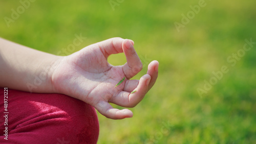 Children meditation with yoga pose on green grass field. Outdoors activity for kids to practicing yoga, children can learn how to exercise, develop confidence and concentrate better.