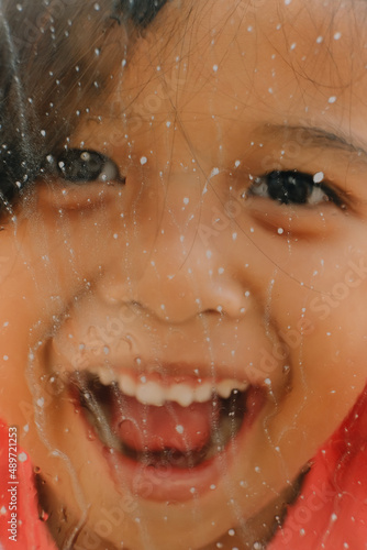 Portrait of a happy little girl behind the glass