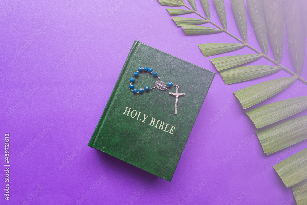 The Holy Bible, cross and palm leaves on purple background. Holy week concept.
