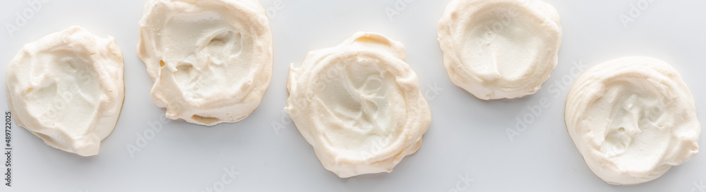 A narrow view of a row of homemade meringues against a white background. A narrow view of a row of homemade meringues against a white background.