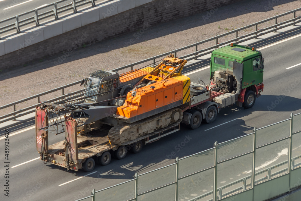 Transportation of a crawler crane on a platform trailer on the road. Transportation of a crawler crane on a platform trailer on the road.