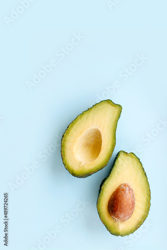 Avocado on blue background. Top view. Banner. Pop art design, creative summer food concept. Green avocadoes, minimal flat lay style.