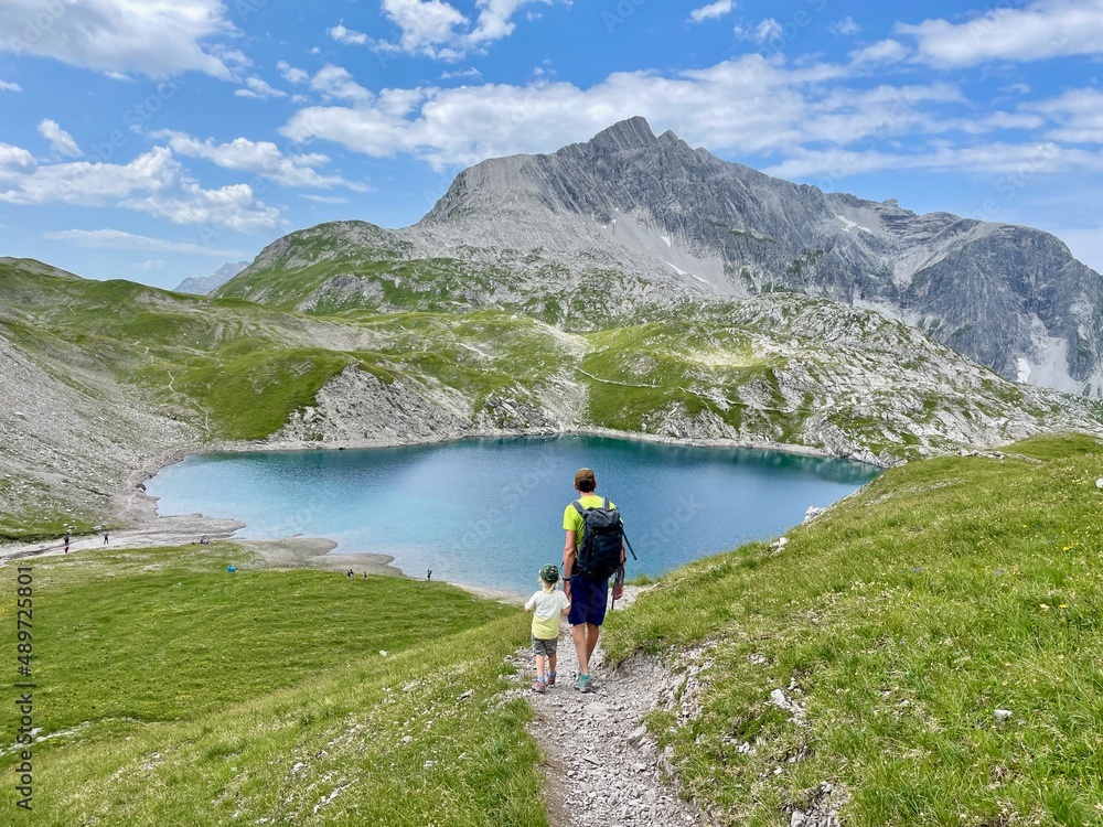 Father and son hiking to beautiful lake Butzen, Butzensee, in Arlberg region close to Lech. Vorarlberg, Austria.