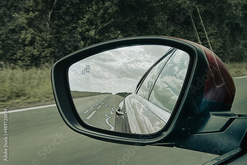 car rearview mirror modern vehicle in road back view and cloudy sky