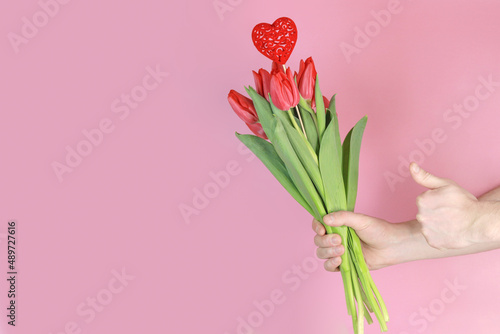 Red tulips in a man's hand on a pink background, gift concept, women's day, love. Space for text © Сергей Стельченко