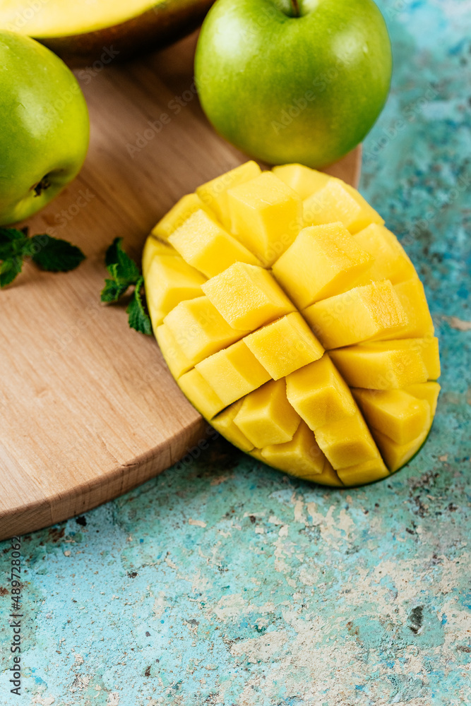 sliced mango and green apples on a light blue background