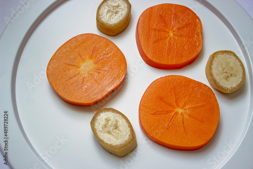 White dish with sliced juicy persimmon slices close-up
