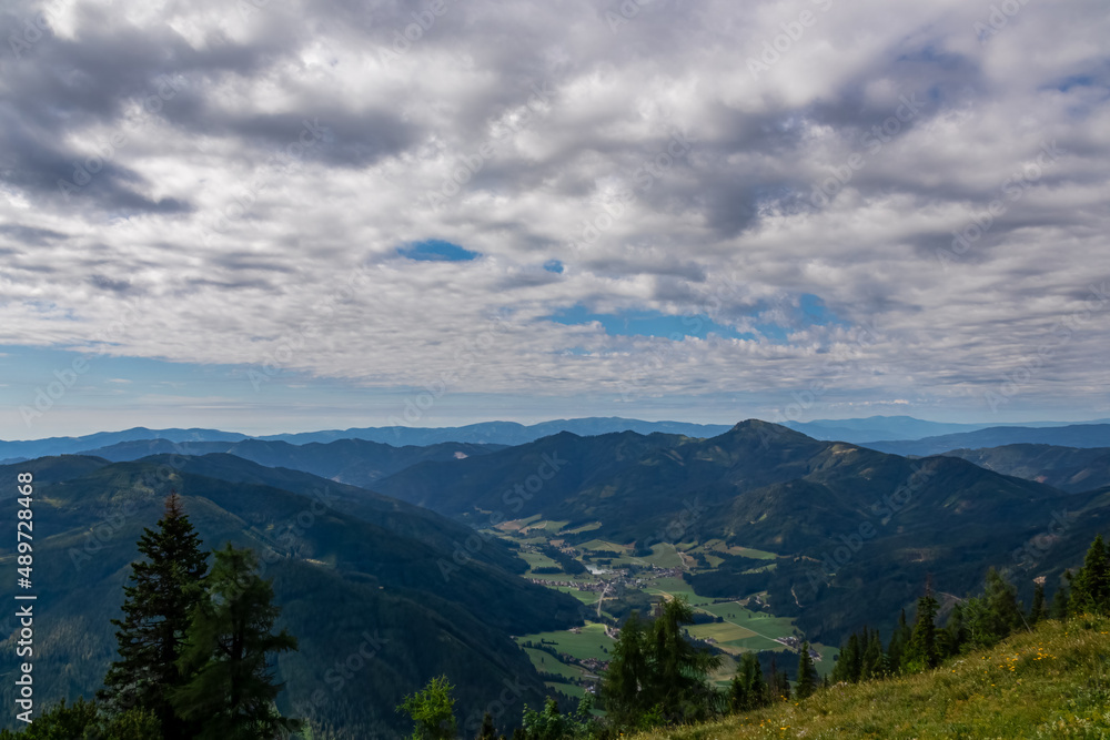 Panoramic view on alpine valley in Hochschwab region in Styria, Austria. Lush green spring meadows. The slopes are partially overgrown with small bushes, higher parts baren. Clear and sunny day.