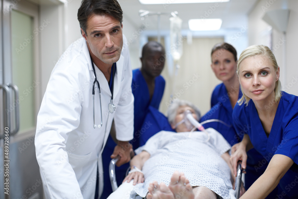 Taking her to the OR. Portrait of a group of doctors pushing a patient down the hall. Taking her to the OR. Portrait of a group of doctors pushing a patient down the hall.