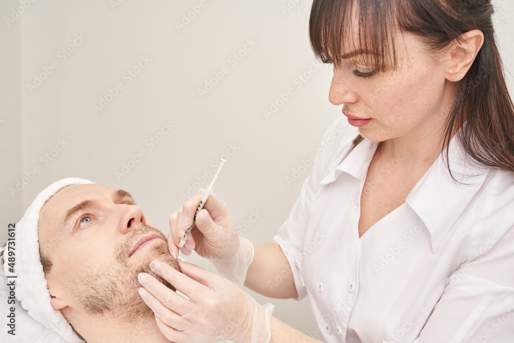 Injection at spa salon. Doctor hands in gloves. Closeup. Pretty male patient. Beauty treatment. Healthy skin procedure. Young man face. Plasmolifting rejuvenation Injection at spa salon. Doctor hands in gloves. Closeup. Pretty male patient. Beauty treatment. Healthy skin procedure. Young man face. Plasmolifting rejuvenation