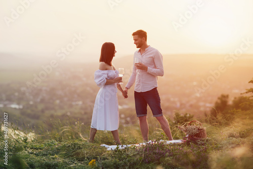 Beautiful young couple holding hands and holding wine glasses at the picnic. Romantic moments