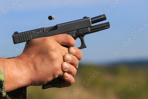 pistol just after firing with an empty cartridge case over the barrel
