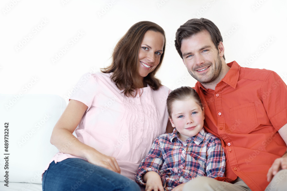 Posing for a family portrait. Portrait of a young family of three sitting on the living room sofa.