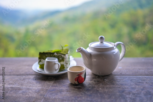 Tea set, Cups and teapot of green tea on wooden board with mountain and forest background
