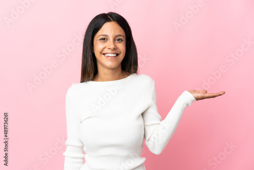 Caucasian girl isolated on pink background holding copyspace imaginary on the palm to insert an ad © luismolinero