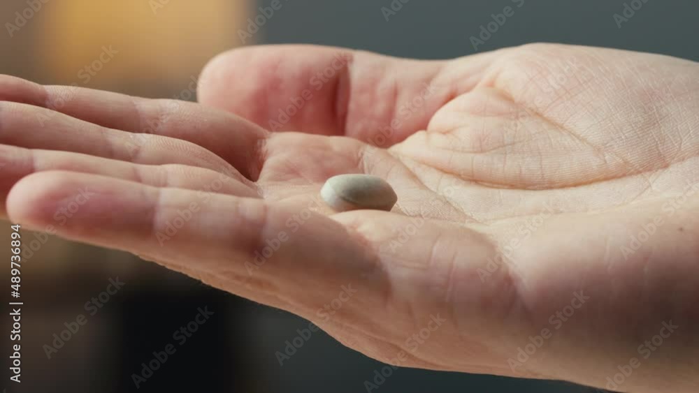 Pill falling into a man's hand in a room at home Pill falling into a man's hand in a room at home