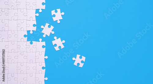 Unfinished white jigsaw puzzle isolated on blue background with copy space photo