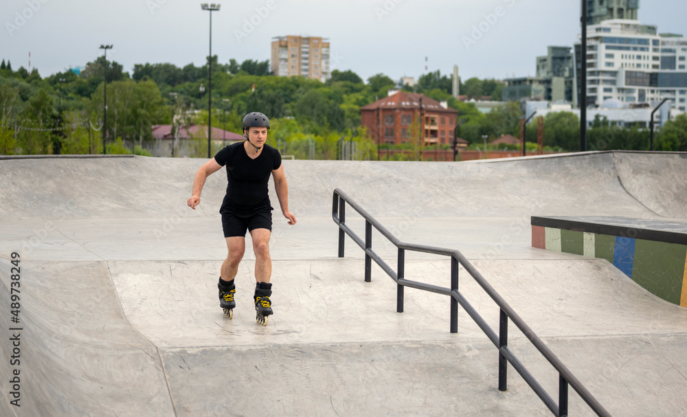 man on rollerblades and in helmet skating on roller coasters in skate park