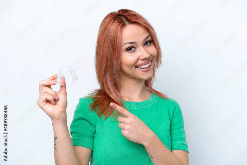 Young Russian girl holding invisible braces isolated on white background and pointing it Young Russian girl holding invisible braces isolated on white background and pointing it