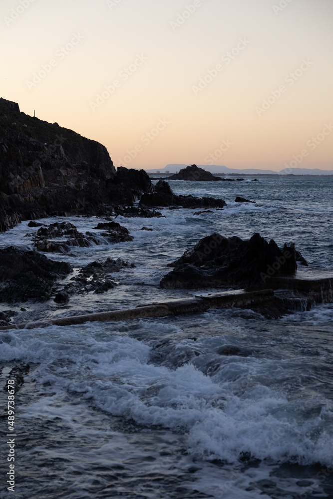Coucher de soleil sur les vagues se fracassant sur les rochers au pied de Collioure (Occitanie, France)