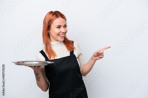 Young Russian waiter with tray isolated on white background pointing finger to the side and presenting a product photo