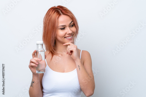 Young Russian girl with a bottle of water isolated on white background thinking an idea and looking side