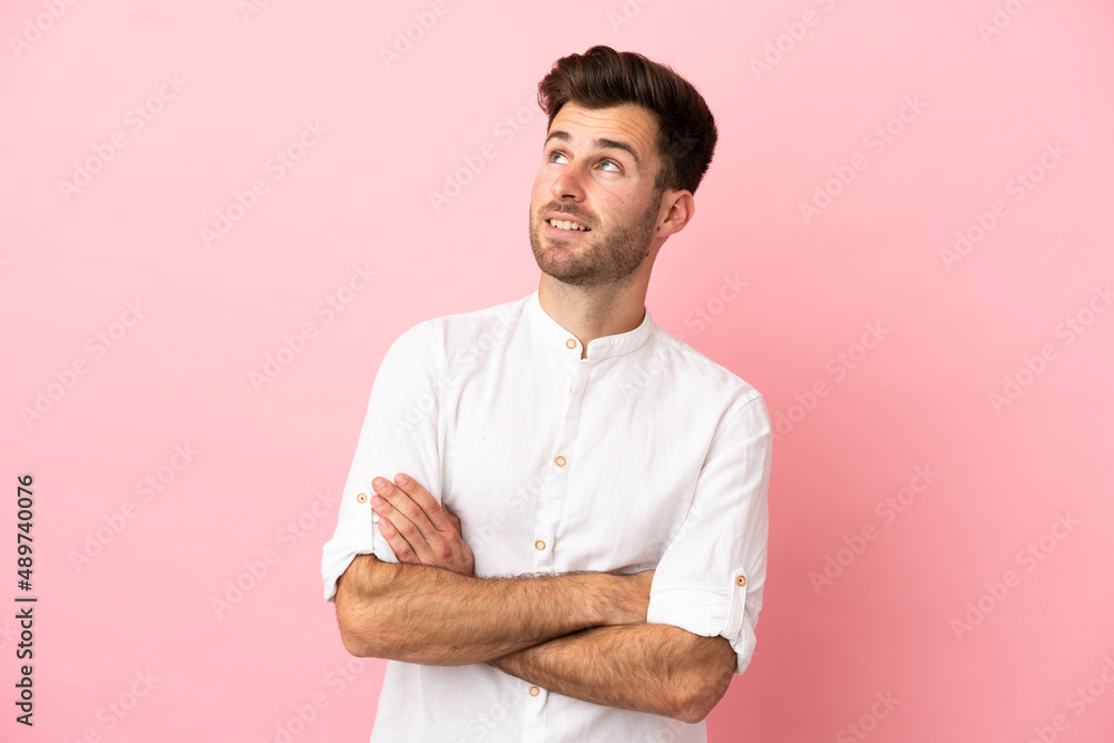 Young caucasian handsome man isolated on pink background looking up while smiling Young caucasian handsome man isolated on pink background looking up while smiling