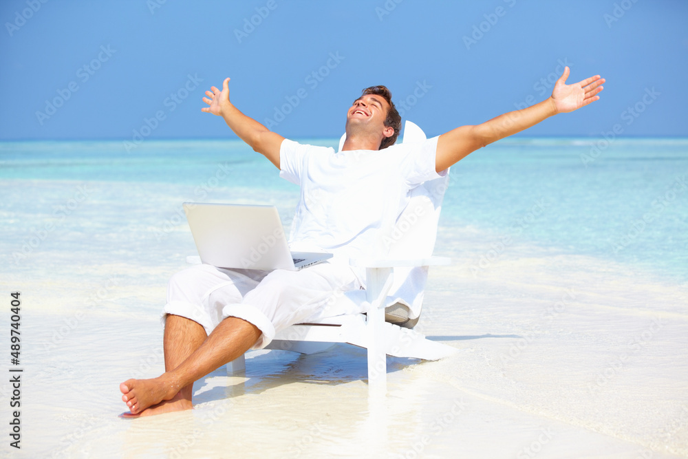Away from hectic life. Portrait of carefree man outstretching his arms with laptop on beach. Away from hectic life. Portrait of carefree man outstretching his arms with laptop on beach.