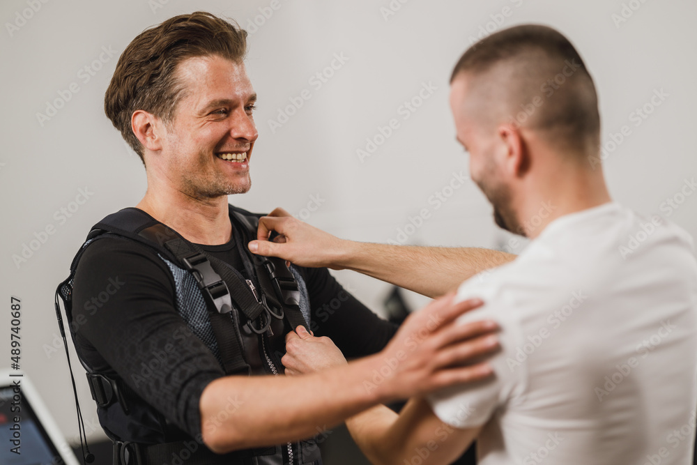 Fitness Instructor Putting An Ems Suit To A Man Fitness Instructor Putting An Ems Suit To A Man