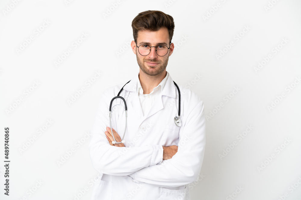 Young doctor caucasian man over isolated on white background wearing a doctor gown and with arms crossed