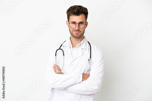 Young doctor caucasian man over isolated on white background wearing a doctor gown and with arms crossed